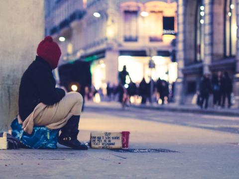 Obdachlose Person sitzt an der Straße