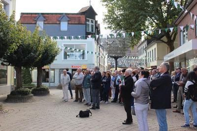 Stadtführer und Teilnehmer auf einer Fußgängerzone mit historischen Gebäuden