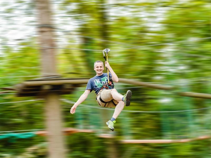 Mann am Seilzug im Kletterwald 