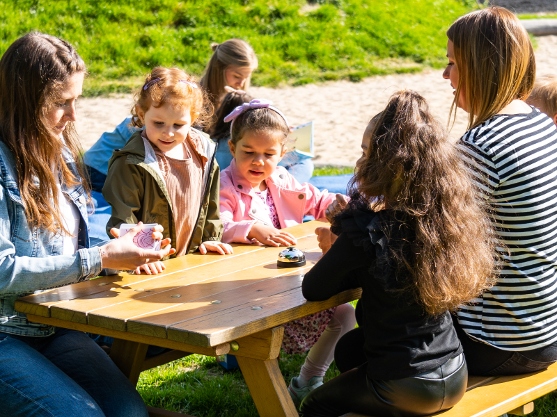 zwei Erzieherinnen mit vier Kindern an Tisch