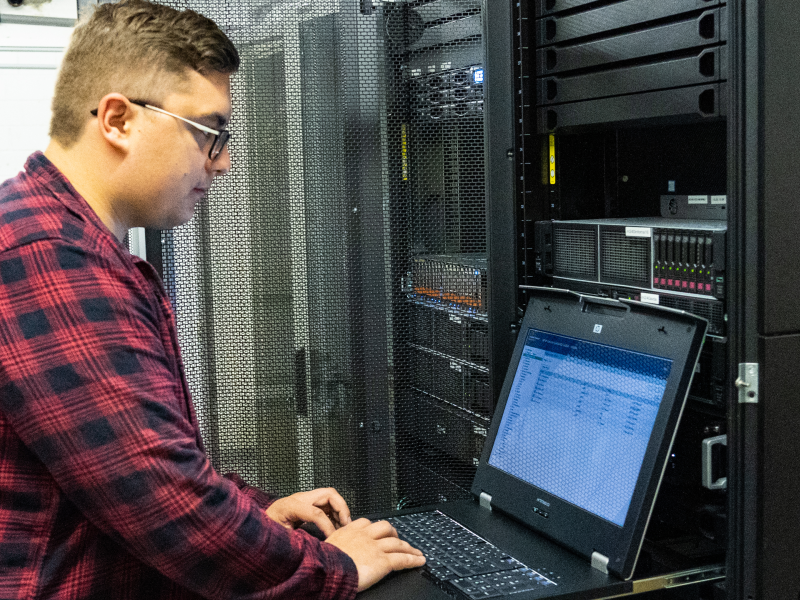 Mitarbeiter mit Laptop in Serverraum