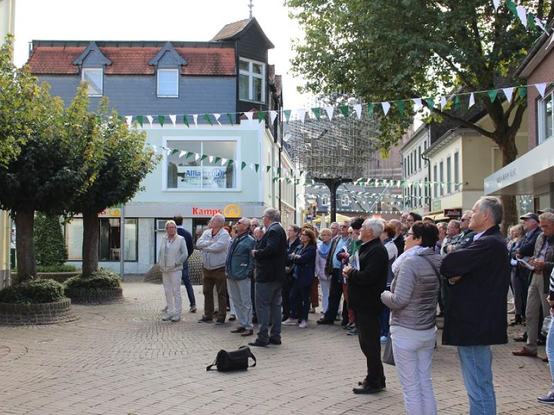 Stadtführer und Teilnehmer auf einer Fußgängerzone mit historischen Gebäuden